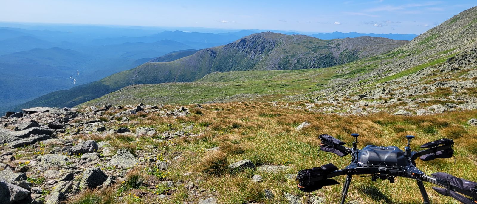 A survey drone on an alpine slope, with ridgelines beyond