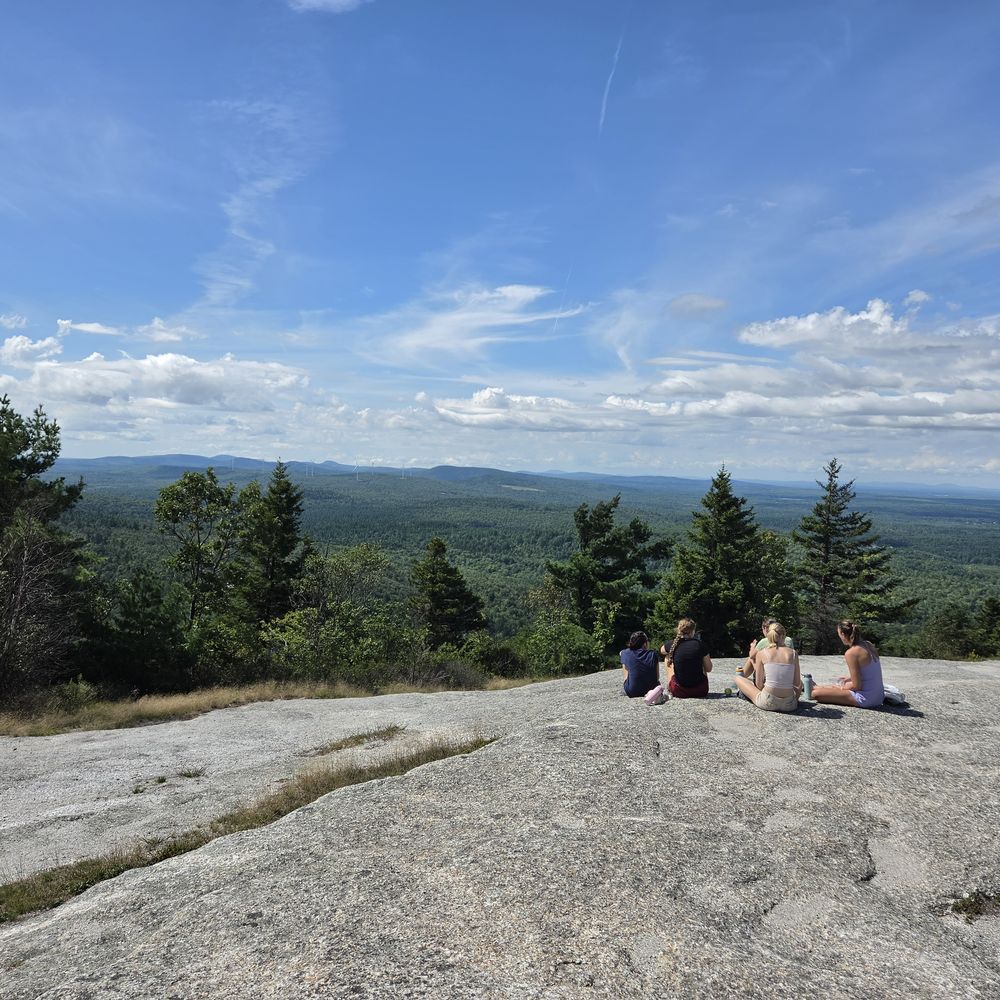 Students resting on a granite summit above forest and lakes