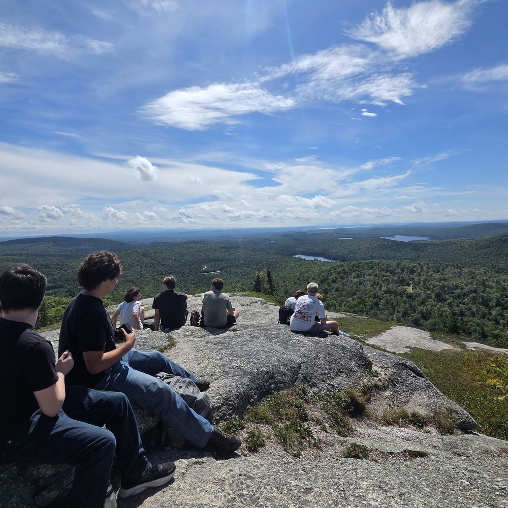 A field course group on a granite summit, looking out over forested hills